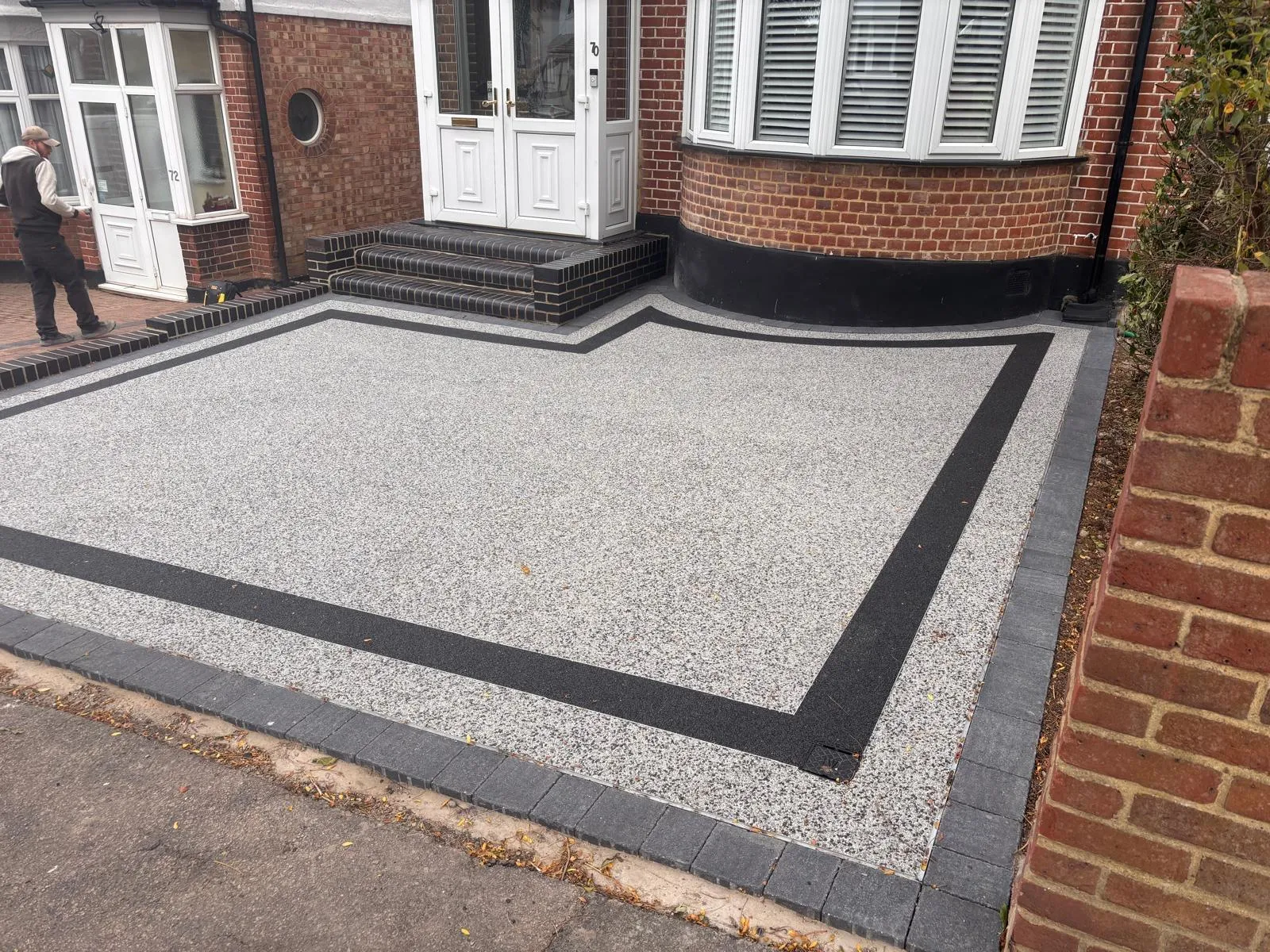A man walking past a brick building with white doors.