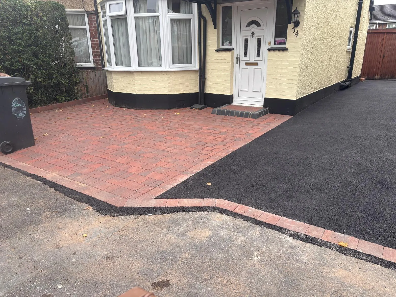 A house with a brick driveway and a white door.