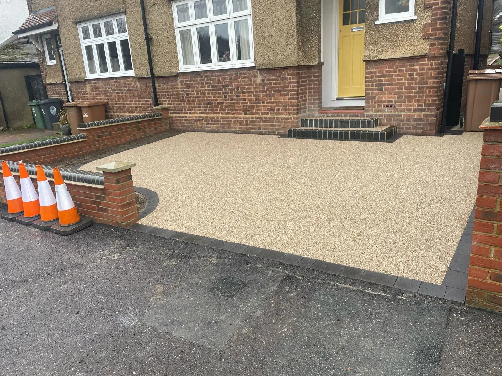 a house with a yellow door and some orange cones in front of it