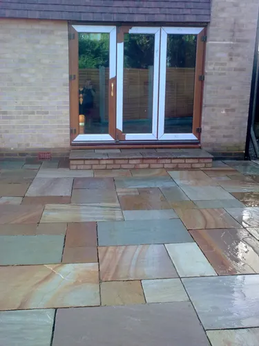 a patio with a stone floor and a brick wall