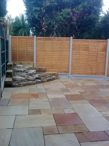 a stone patio with a wooden fence in the background