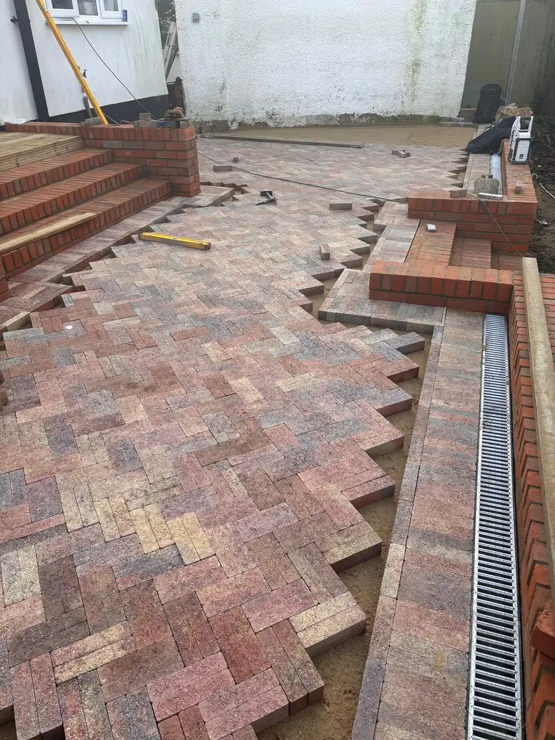 A brick patio being built in a back yard.