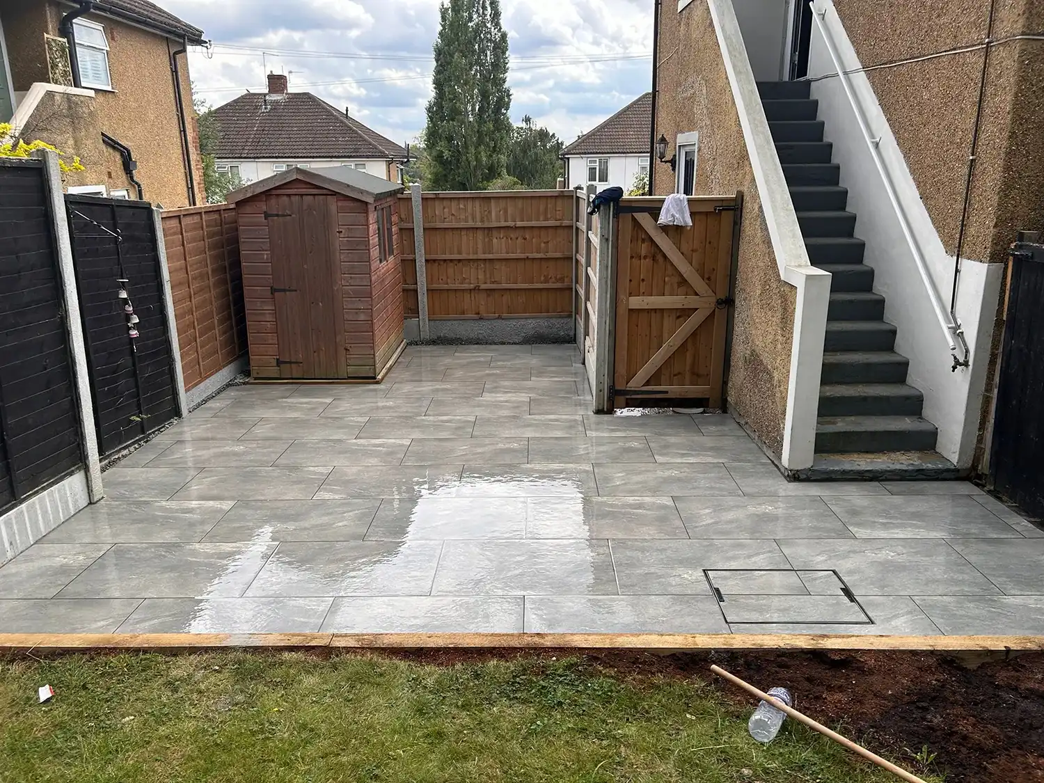 A back yard with a concrete patio and stairs.