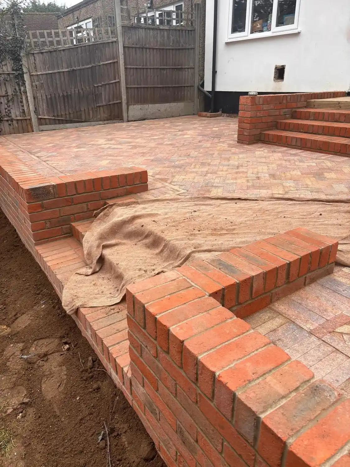 A brick patio being built in a back yard.