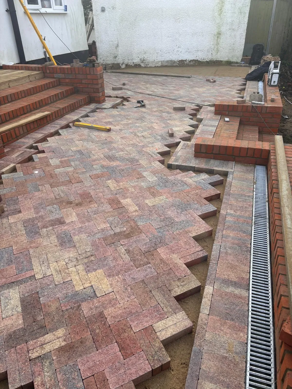 A brick patio being built in a back yard.