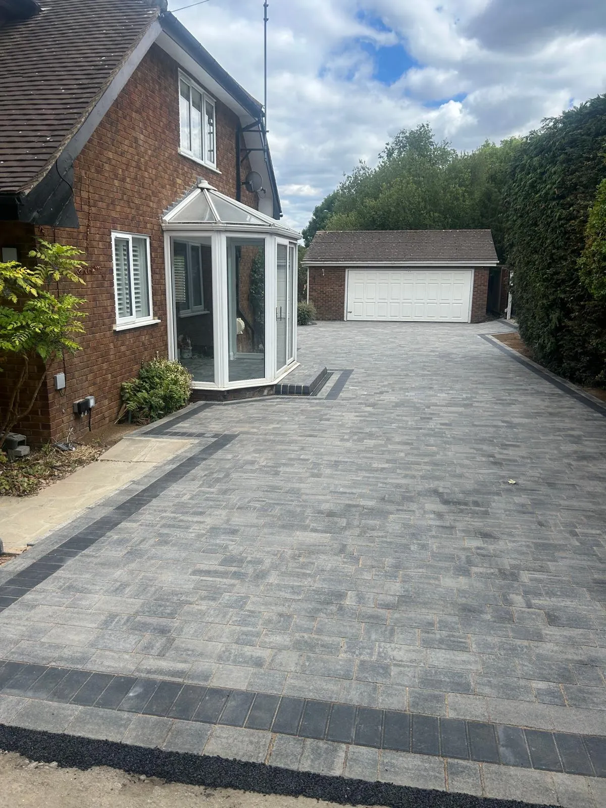 A brick driveway with a white house in the background.