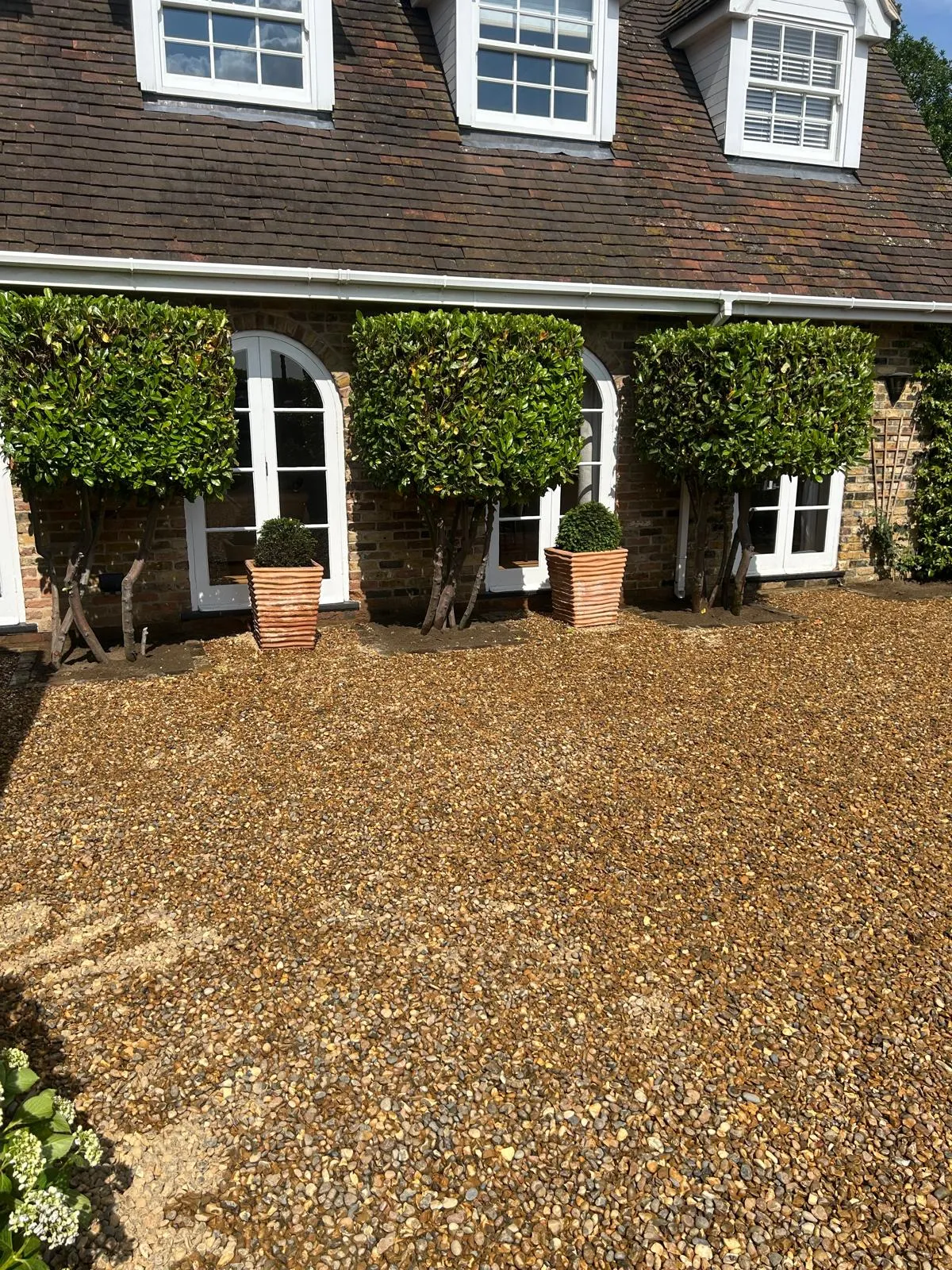 A house with a large gravel driveway and white windows.