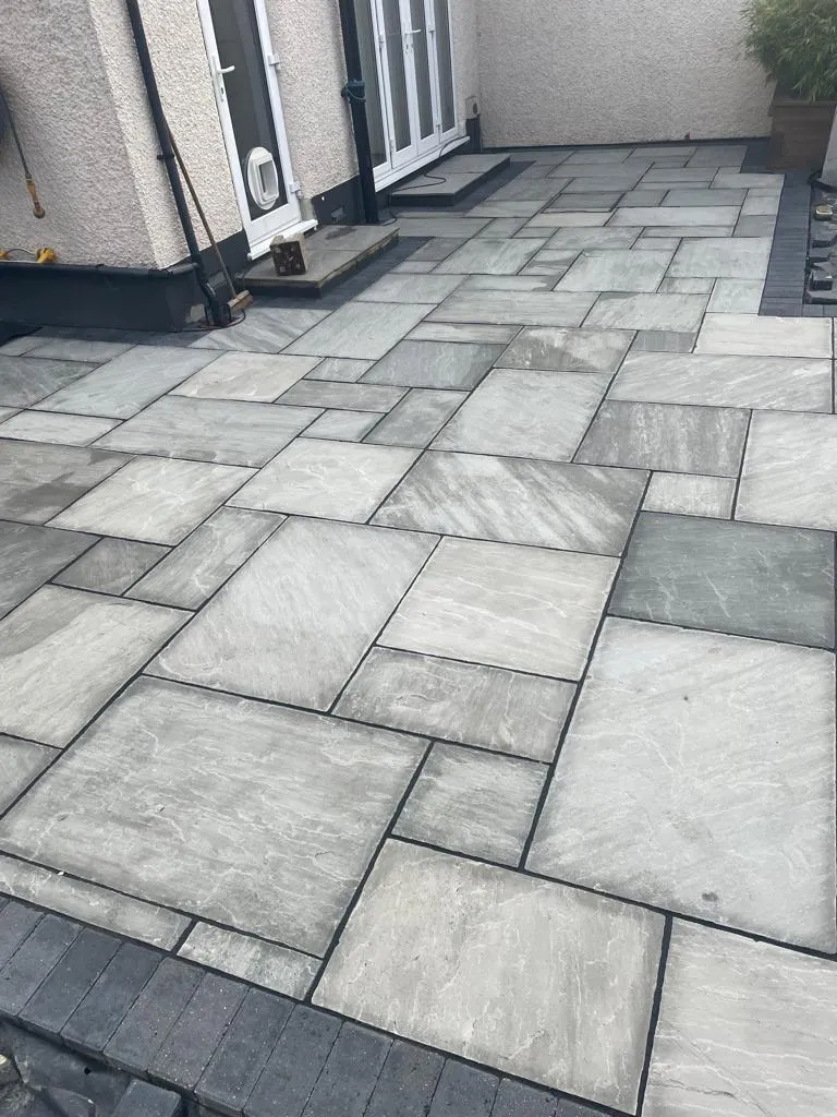 a stone patio with a black door and steps