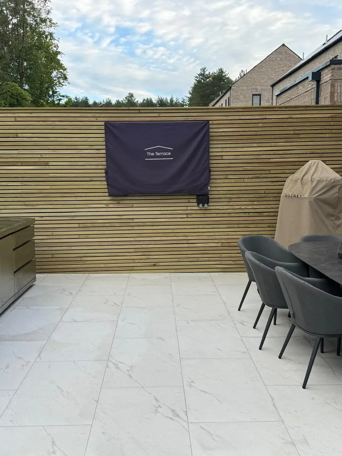 a patio with a table and chairs and a grill