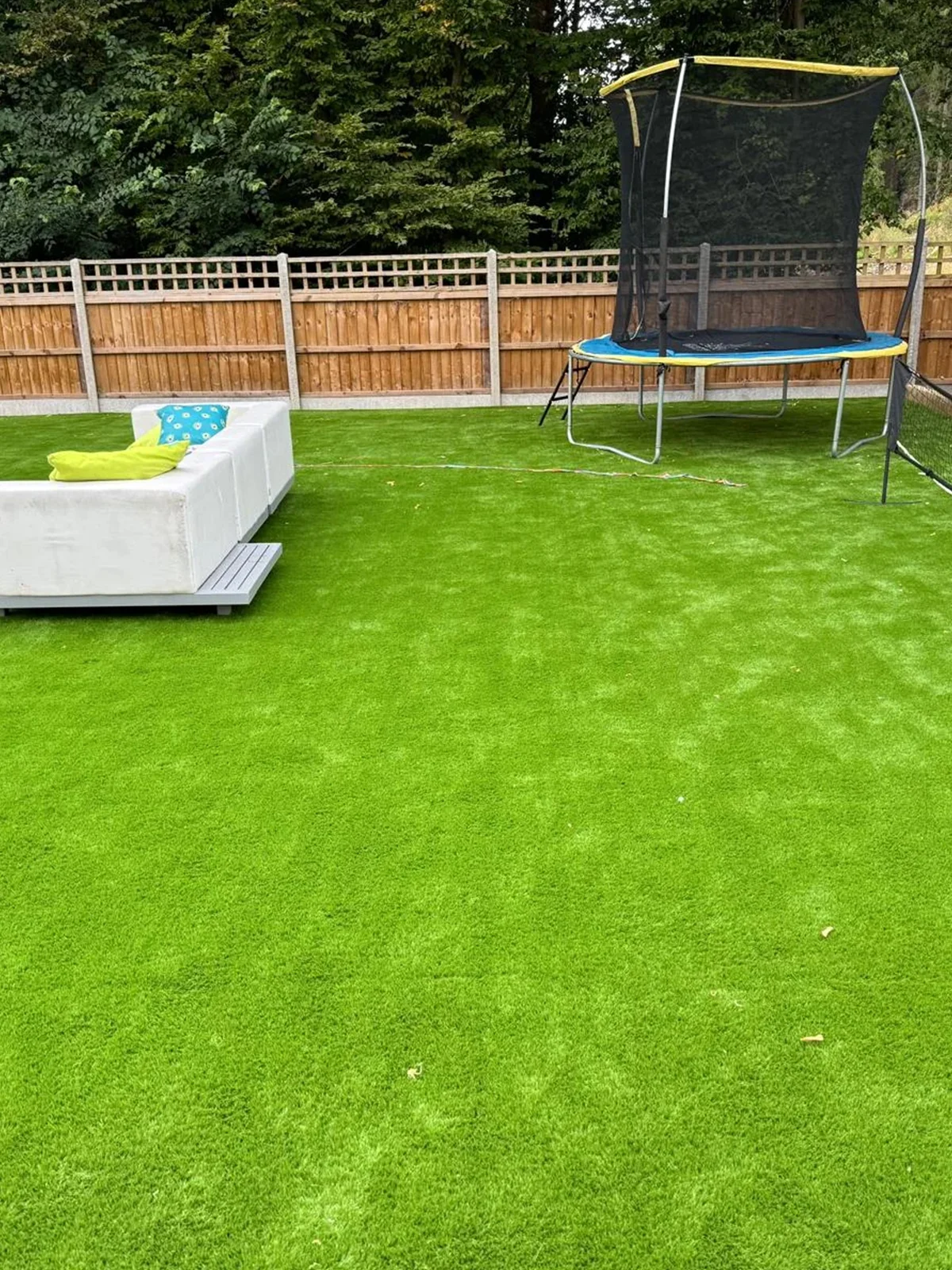 a backyard with artificial grass and a trampoline