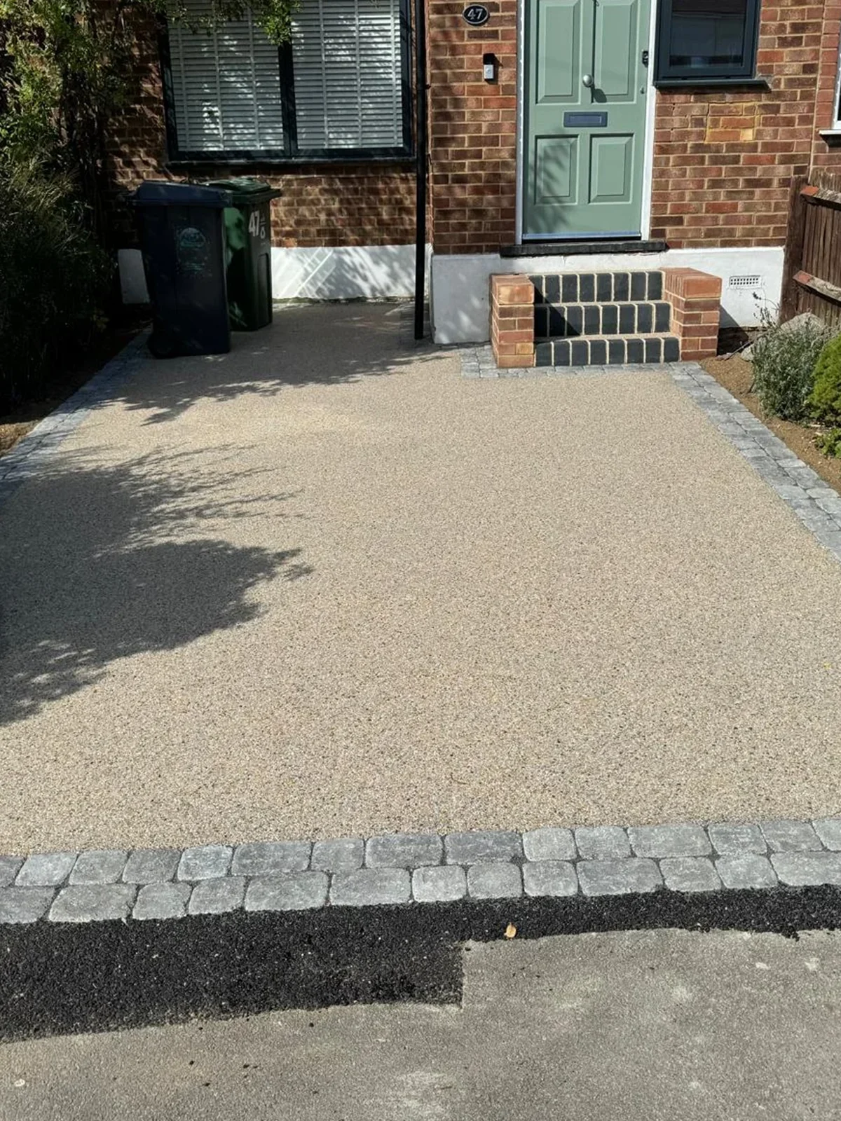 A driveway with a brick border and a green door.